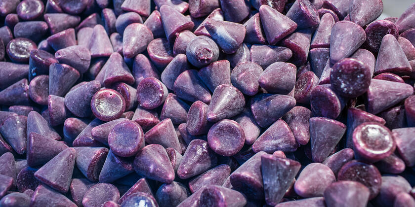 A picture filled with numerous cuberdons: coneshaped and purple candy.