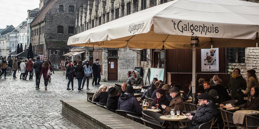 Groot terras van café 't Galgenhuis, met comfortabele rotan stoelen en bescherming door parasols.