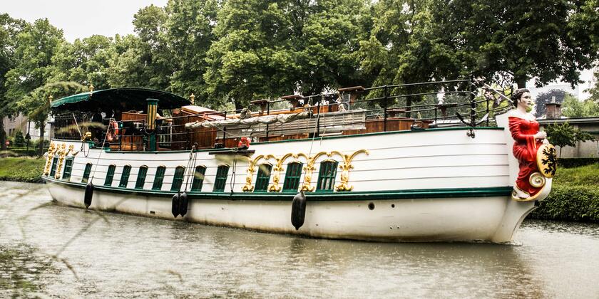 Het prachtig gerestaureerde houten schip 'De Barge' in wit, goud en groen met de 'Maagd van Gent' en het wapenschild van Gent als boegbeeld.