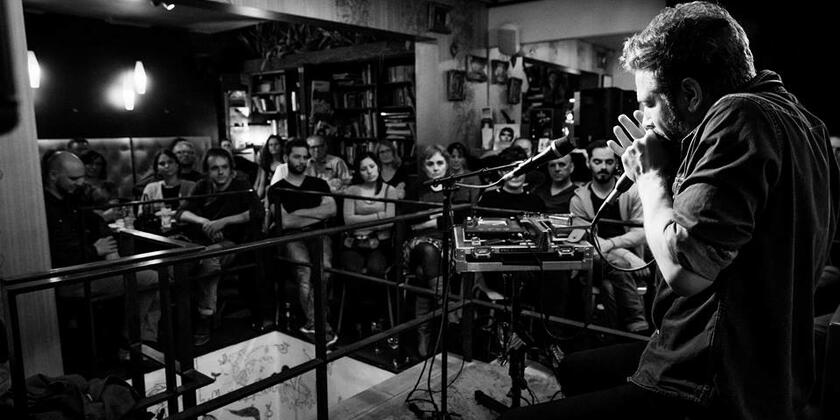 zwart-witfoto van een groep klanten die luisteren naar een live optreden
