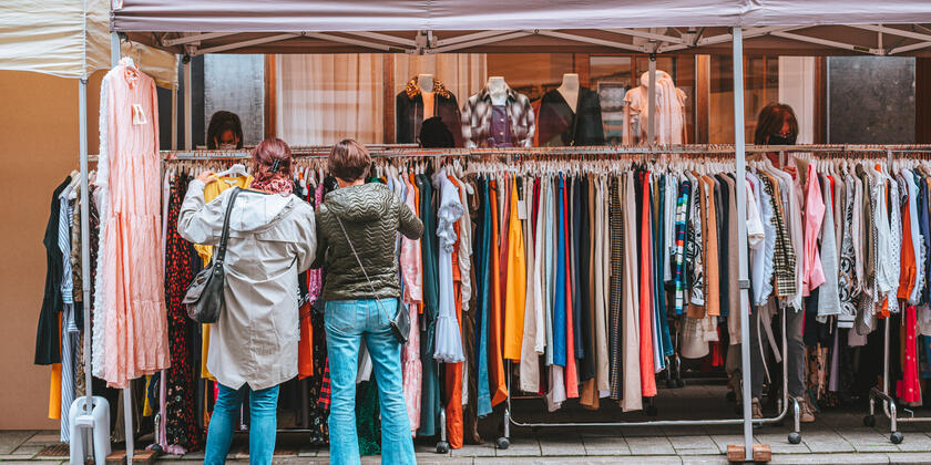 Zwei Damen suchen auf dem Markt Kleidung aus
