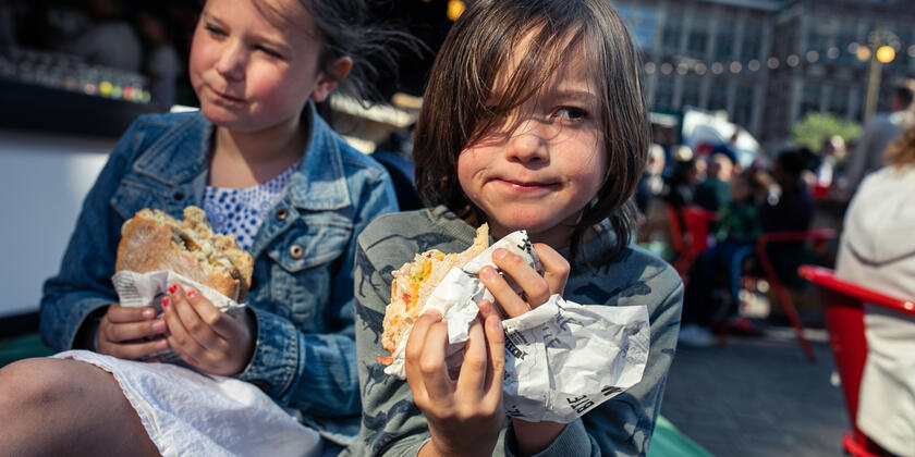 Jongen en meisje eten een hamburger uit het vuistje
