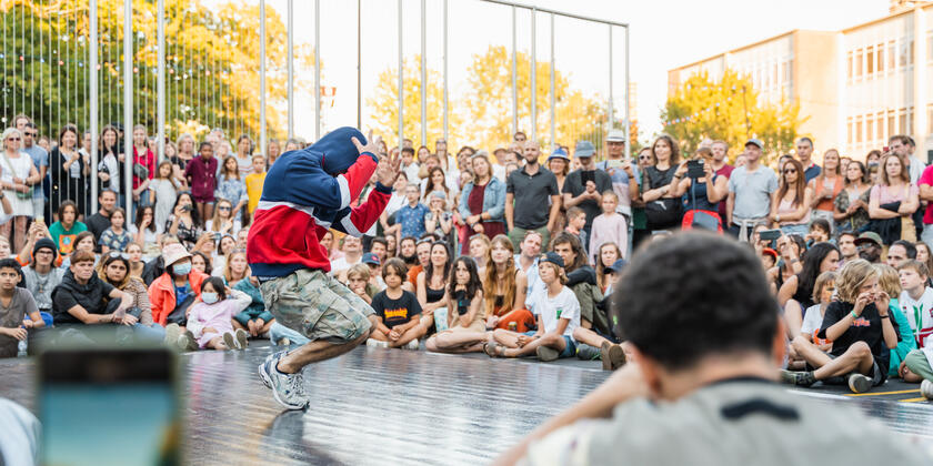 Breakdancer op podium met publiek in achtergrond