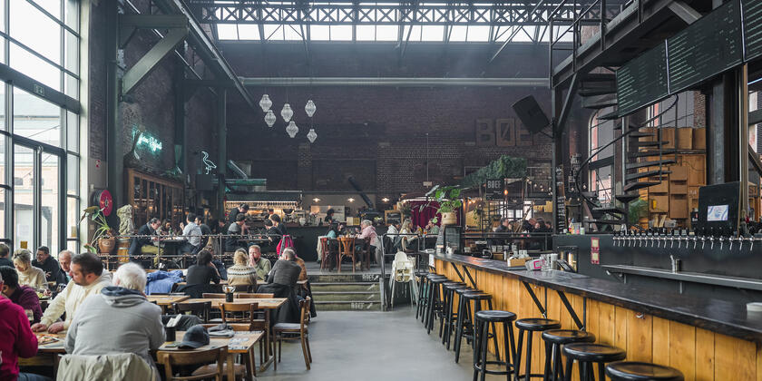 Foodhal in industrieel gebouw met tal van tafeltjes vol gasten