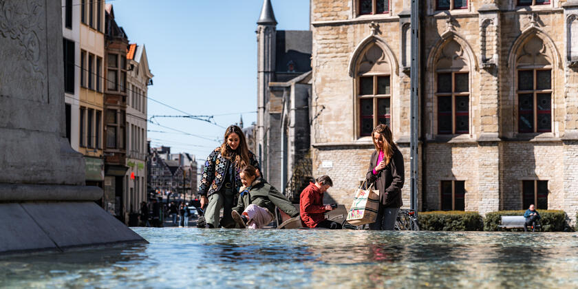 Tiany und Familie am Brunnen am Sint-Baafsplein in Gent an einem sonnigen Tag