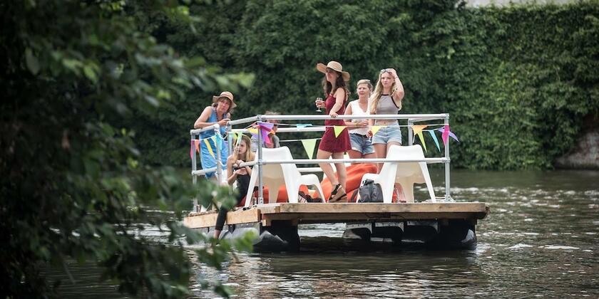 6 Personen fahren auf dem Fluss mit einem Floß mit Reling und Stühlen