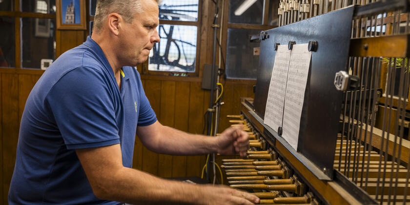 Beiaardier Ken Theunissen bespeelt het klavier dat bestaat uit stokken en pedalen, verbonden met de klepels in de klokken