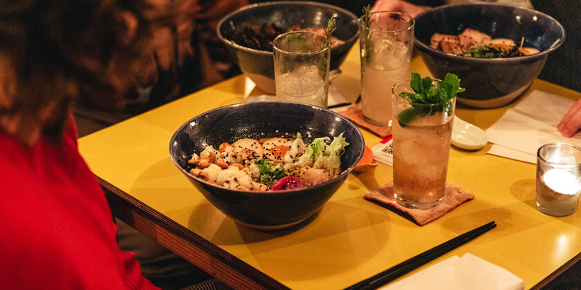 A full table with a dark & stormy cocktail and vegetarian tantan ramen