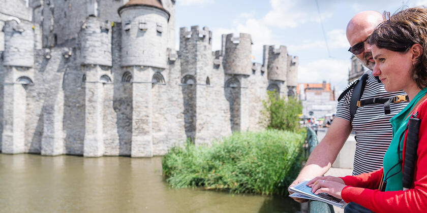 Dame met visuele beperking maakt gebruik van de wandelgids met voelplaten tijdens haar wandeling langs het Gravensteen