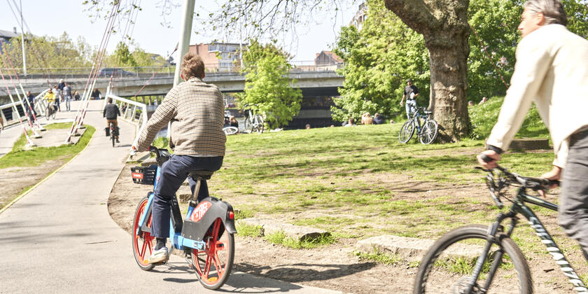Twee fietsers rijden naar de fietsersbrug in het Keizerspark in Gent op een mooie zonnige dag