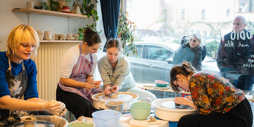 4 vrouwen zitten elk voor een draaitafel met keramiek