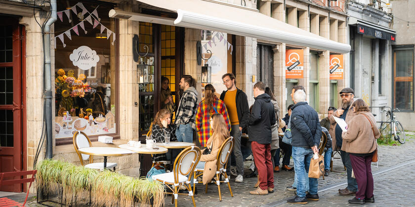 een groep mensen staan te wachten aan de ingang van een horecazaak