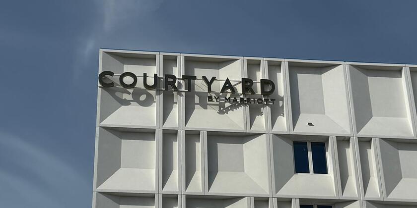 Witte buitengevel van het hotel met een blauwe lucht op de achtergrond 