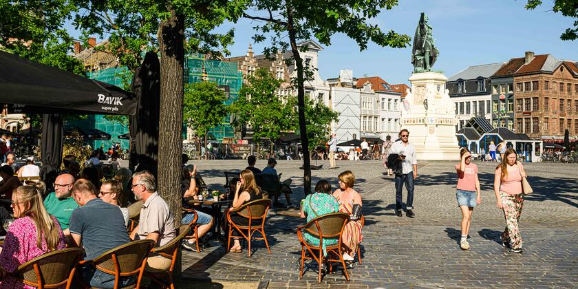 Mensen op een terras in de zon aan de Vrijdagmarkt