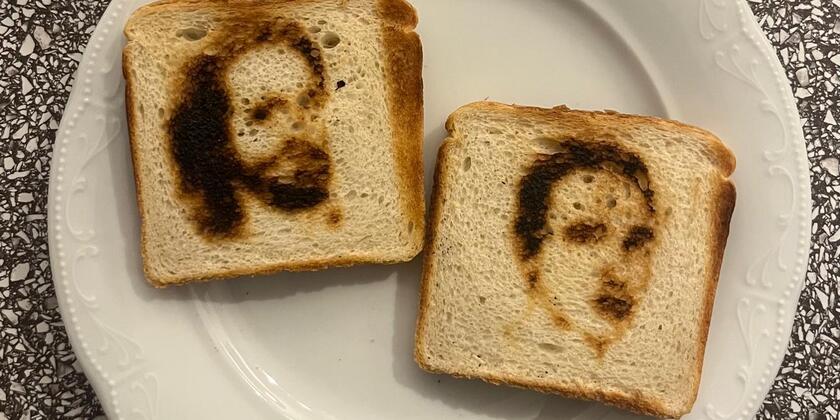 Ein weißer Teller mit zwei Scheiben Toastbrot. Auf jeder Scheibe ist ein Männergesicht abgebildet.