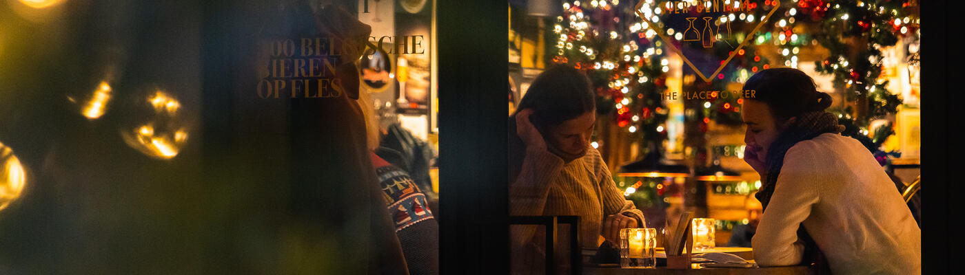Paar an einem Tisch mit Weihnachtsbeleuchtung am Fenster