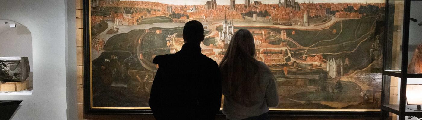 Sarah und ihr Freund betrachten ein Gemälde, das die Geschichte von Gent im STAM erzählt