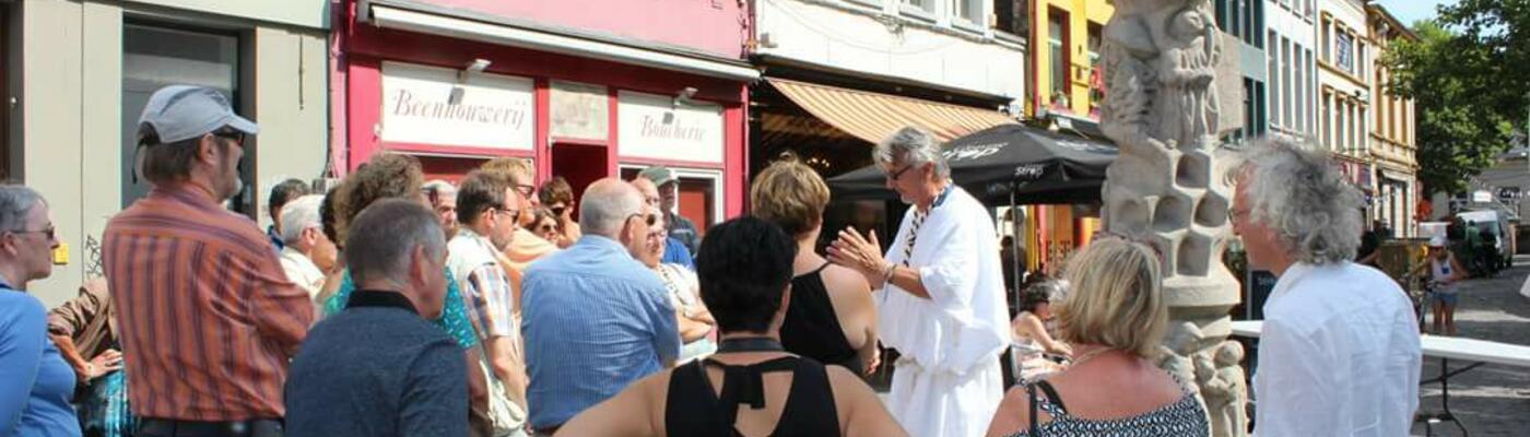 mensen staan te luisteren naar een gids verkleed in wit gewaad