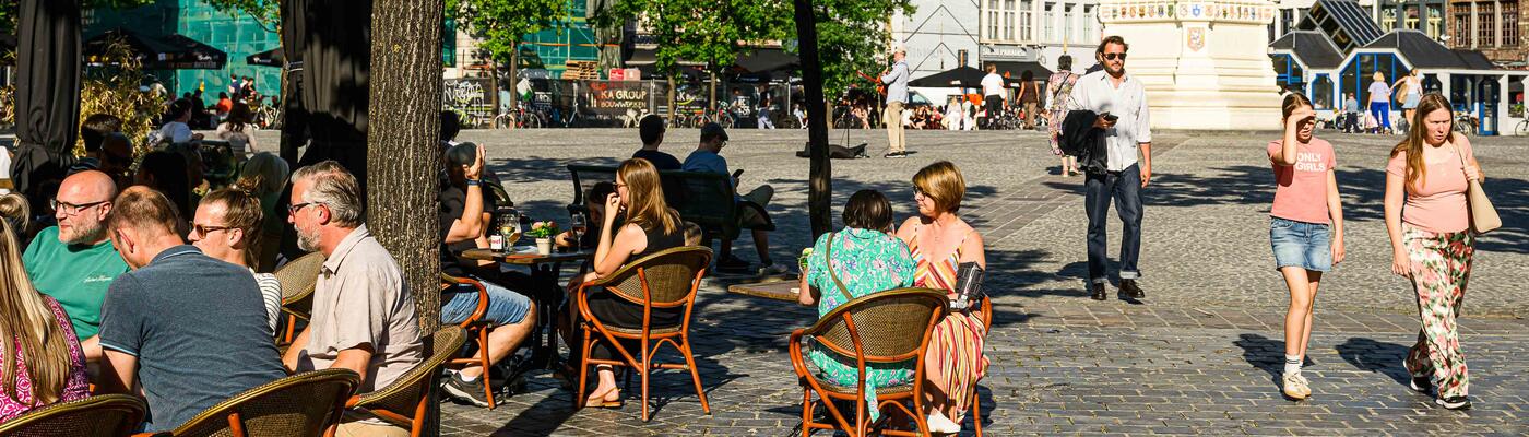Mensen op een terras in de zon aan de Vrijdagmarkt