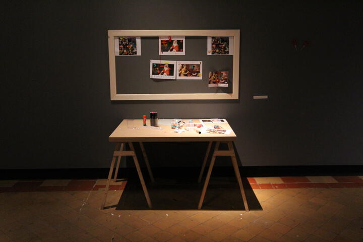 een tafel tegen een grijze muur met een kader met daarin verschillende foto's