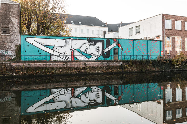 street art van een man met een rood potlood en weerspiegeld in het water