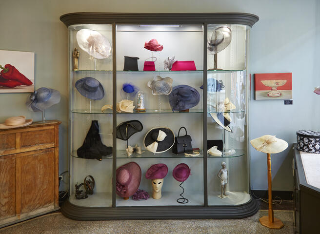 een vitrinekast met hoeden in verschillende kleuren