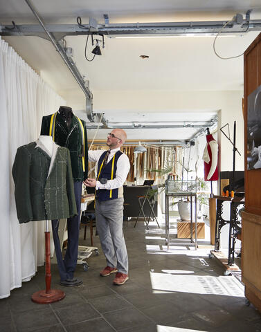 een man die in een atelier aan het werk is met kledij