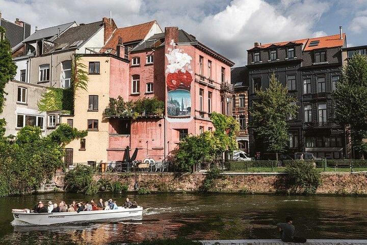 een bootje op het water dat voorbij een gebouw met street art vaart
