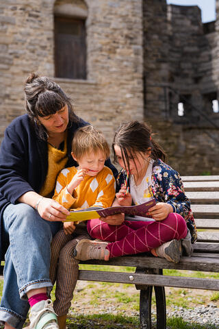 Gezin leest het Little Guide boekje op bankje aan het Gravensteen