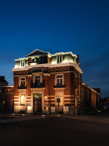 Verlichte art-deco gevel van het Van Eyck zwembad in Gent bij valavond