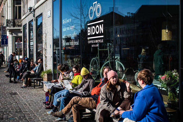 Mensen genieten in dikke jas en met mutsen van een terrasje aan de Reep in Gent