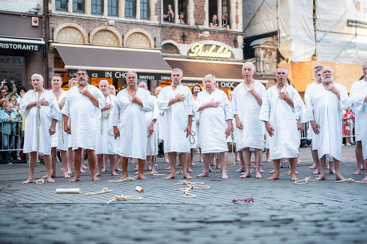 Hombres con túnica blanca con una eslinga alrededor del cuello durante el stroppenstoet de las festividades de Gante