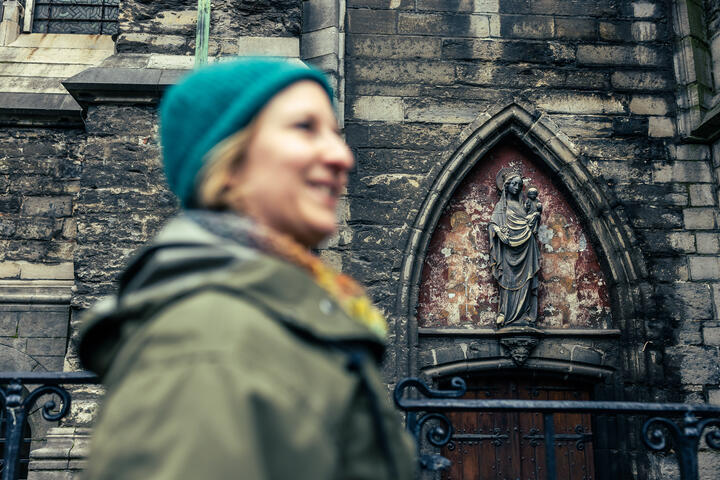 Maaike Blancke geht an den Fassaden der St.-Bavo-Kathedrale in Gent entlang