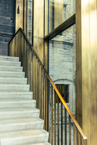 Un escalier en béton avec une rampe en laiton indique aux visiteurs le chemin à suivre dans le nouveau centre d'accueil de la Cathédrale Saint-Bavon.