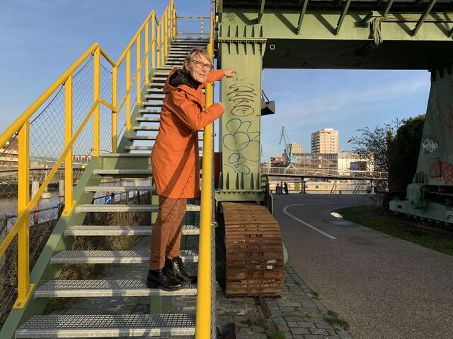 Grietje stands on a metal staircase at the foot of a crane