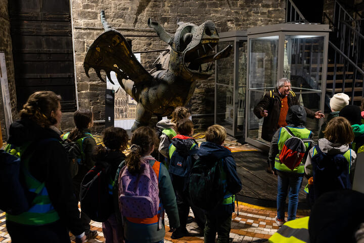 Een gids geeft uitleg aan een groep kinderen bij de draak in het Belfort