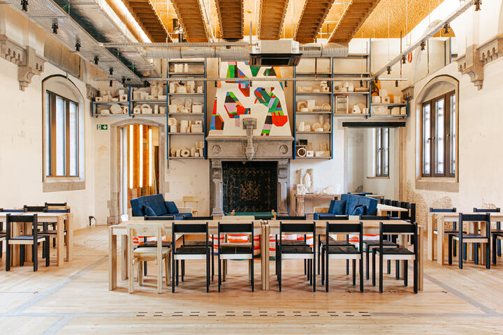 Grote zaal met lange houten tafel en stoelen met een openhaard op de achtergrond