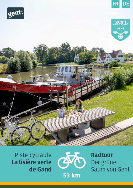 ©De Fietsambassade Deux femmes sont assises à une table de pique-nique au bord d'une rivière.