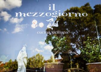 Beschilderd raam met de naam en het opschrift 'cucina siciliana'.
