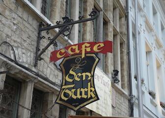 Uithangbord in smeedijzer van Café Den Turk, gouden letters op zwart veld.