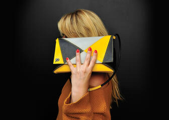 Zwart-gele trendy handtas geshowed door blonde dame