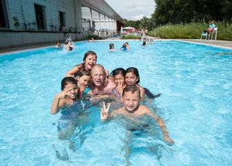 Buitenzwembad van de Rozebroeken met groep kinderen en begeleider centraal in de foto.