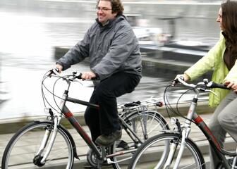 Twee fietsers rijden langs het water.
