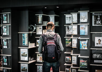 Young man with a backpack looking for information in the documentation cabinets of the tourist information office