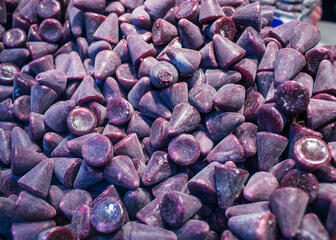 Een foto gevuld met tientallen cuberdons: kegelvormige, paarse snoepjes.