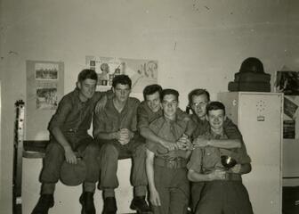 zwart-wit foto van 6 mannen in uniform aan een stapelbed 