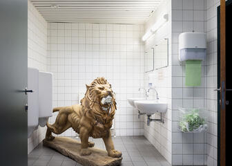 toiletruimte met piscines, lavabo's, spiegels en een beeld van een leeuw