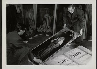zwart-wit foto van 2 mannen die een luik van het lam gods vasthouden
