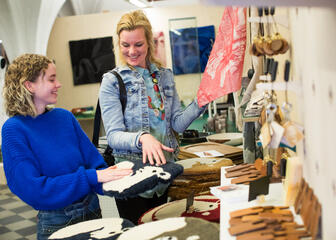 Vrouw en tienermeisje bekijken artikelen in de Van Eyck-shop