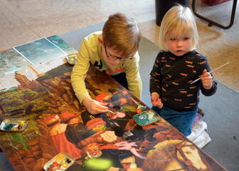 2 kinderen die op een schilderij van het lam gods aan het schilderen zijn